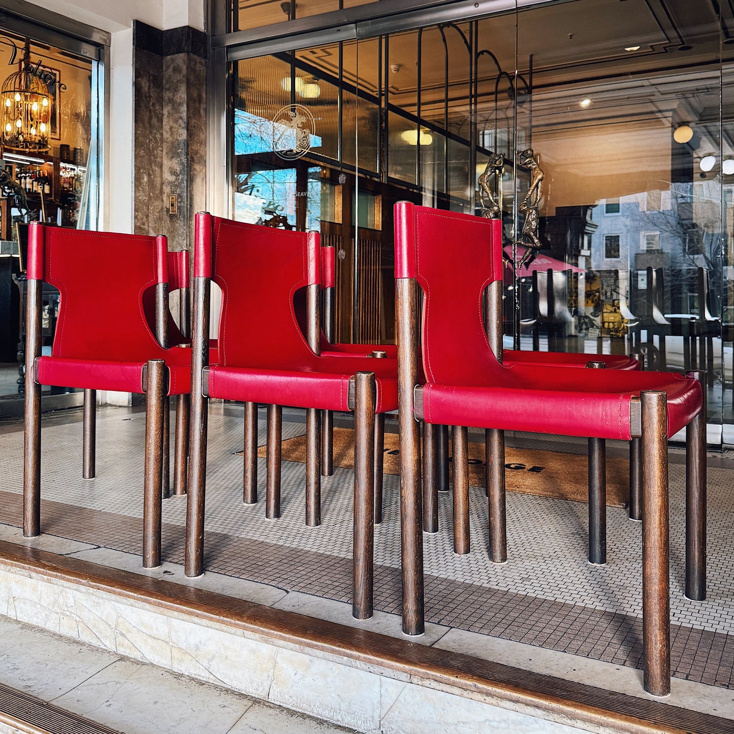 Red chairs in a restaurant window display with reflections of the interior.